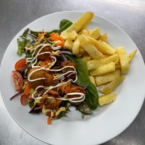 Plated main serving of battered garlic mushrooms salad, chips and dressing